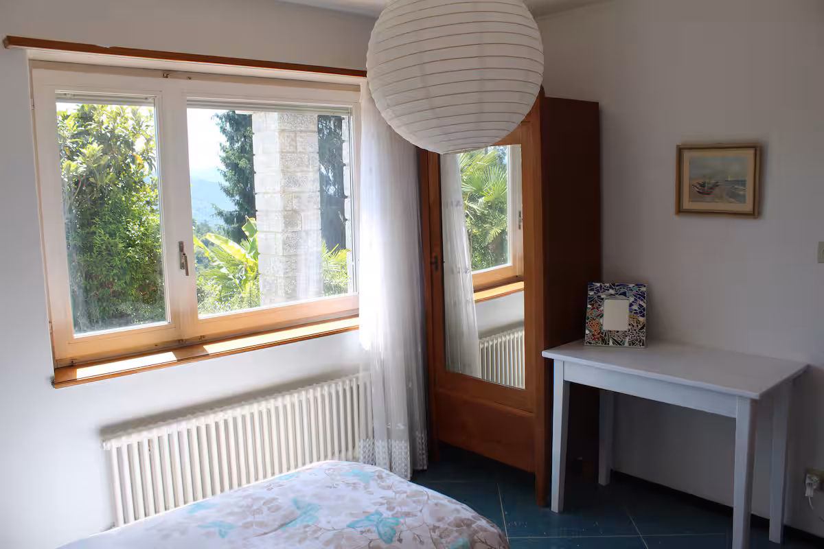 Chambre avec fenêtre sur la verdure, miroir et suspension en lanterne