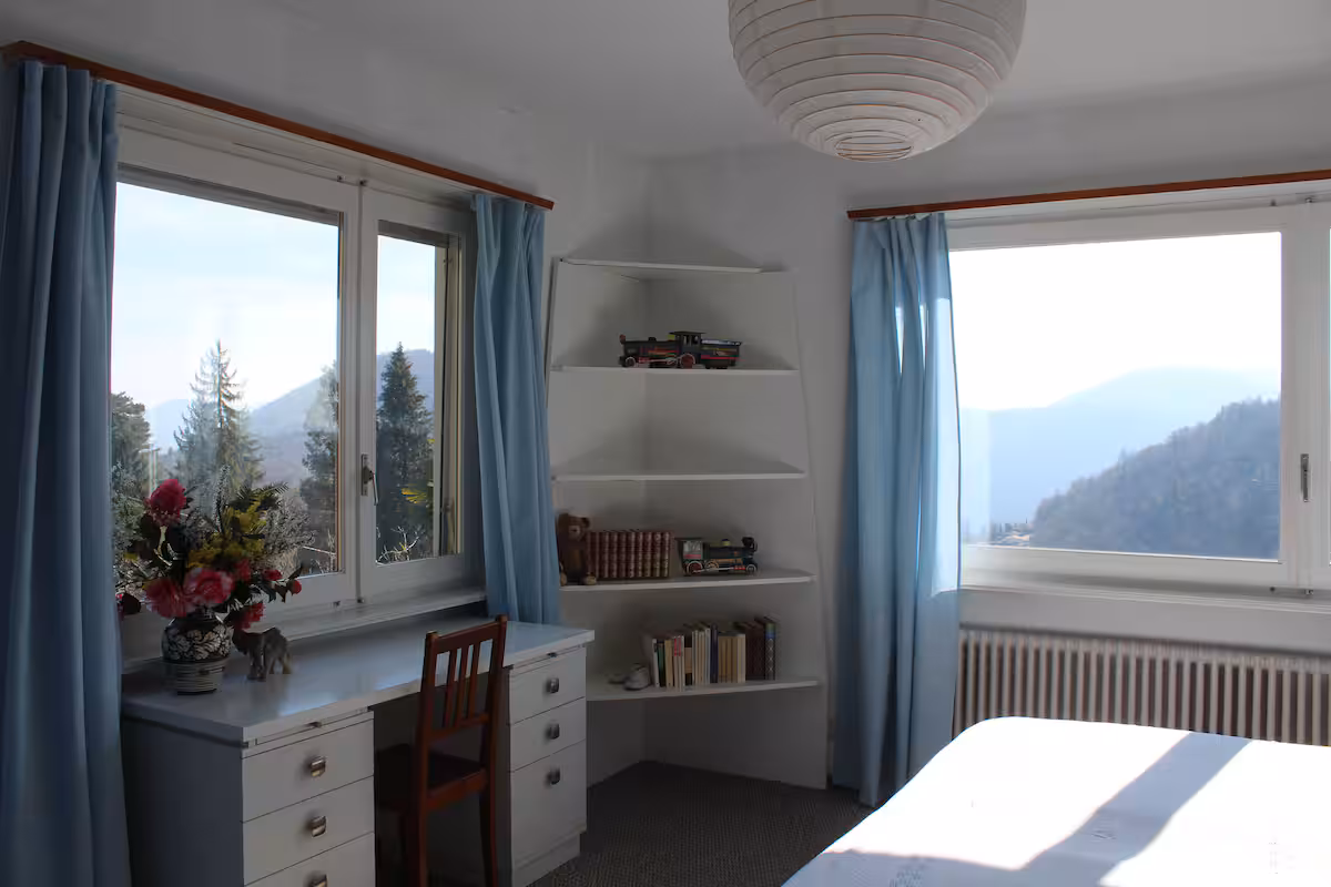 Chambre avec bureau blanc et fenêtre donnant sur le jardin