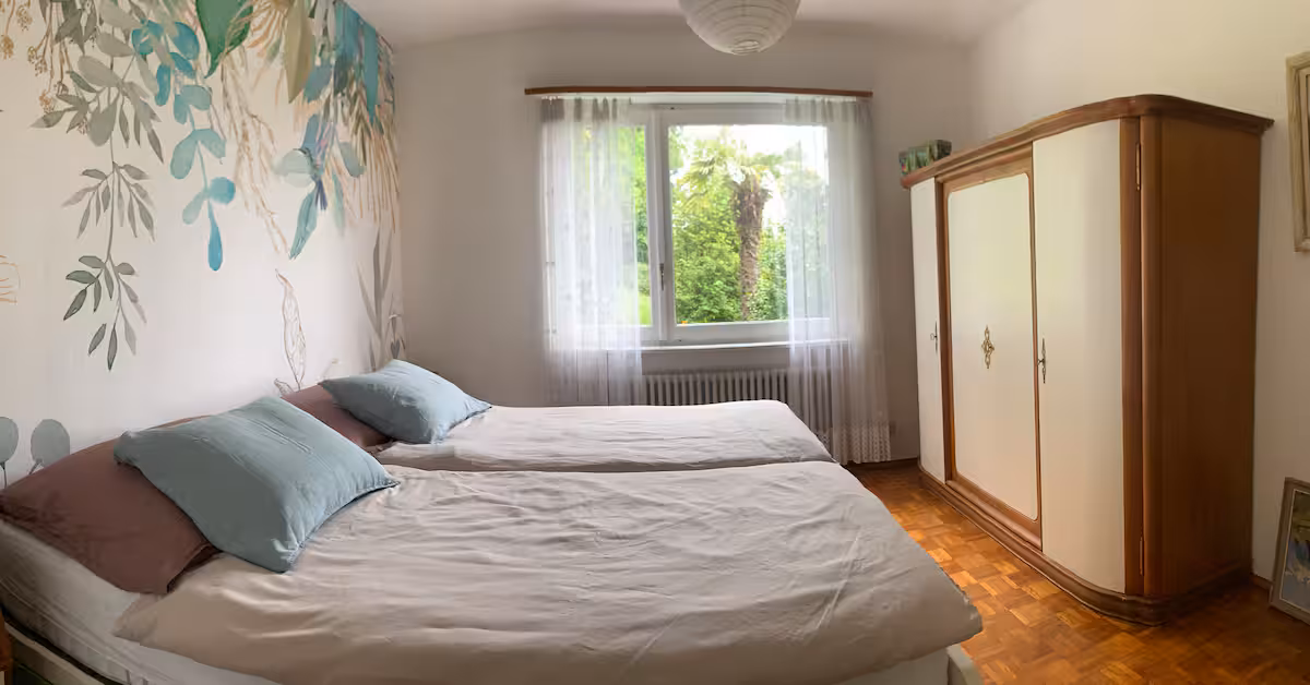 Chambre spacieuse avec armoire blanche et parquet