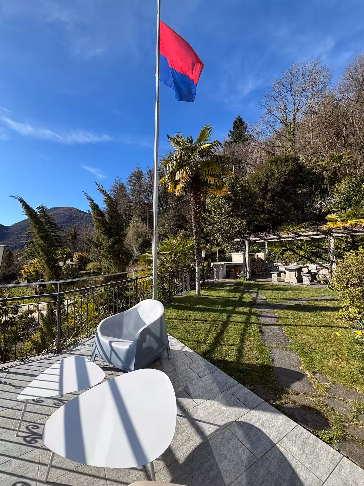 Terrasse de la villa avec mobilier de jardin blanc et table en pierre sous la pergola, vue sur les montagnes